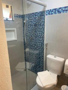 a bathroom with a toilet and a glass shower at Pousada Kainoa in Ilha do Mel