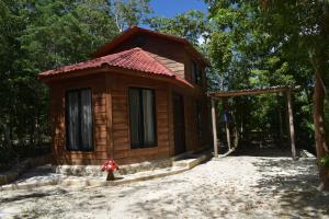 Cabaña de madera pequeña con techo rojo en Eco Aldea kinich Ahau, en Xpujil