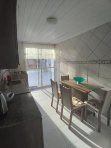 cocina con mesa, sillas, mesa y barra en Casa com piscina Laranjal, en Pelotas