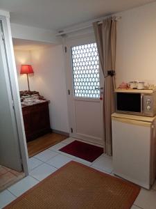 a room with a kitchen with a microwave and a door at Au Calme in Verneuil d’Avre et d’Iton