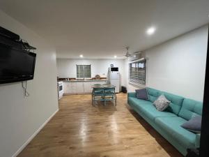 uma sala de estar com um sofá azul e uma mesa em CBR Equine Cottage em Amamoor
