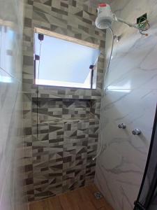 a bathroom with a shower with a window at Flat com Varanda - Avenida Hospedagem in São Thomé das Letras