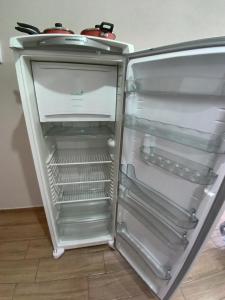 an empty refrigerator with its door open at Flat com Varanda - Avenida Hospedagem in São Thomé das Letras