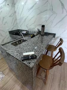 a kitchen counter with a sink and a wooden chair at Flat com Varanda - Avenida Hospedagem in São Thomé das Letras