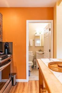 シアトルにあるThe Perfect Spot - Capitol Hill, DT, Central Dist.のオレンジ色の壁のキッチン、トイレ、シンクが備わります。