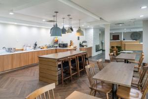Fairfield Inn & Suites Beaumont في بومونت: مطبخ وغرفة طعام مع طاولات وكراسي خشبية