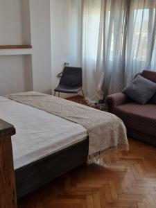 a bedroom with a bed and a chair and a window at Blue New Yorker in Niš