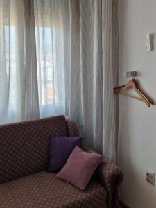 a couch with two pillows in a room with a window at Blue New Yorker in Niš