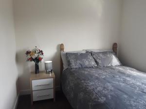a bedroom with a bed and a table with a vase of flowers at HAMS REST PLACE - Strictly Only ONE GUEST ALLOWED IN ONE ROOM A SECOND ACCOMPANYING PERSON WILL NOT BE ALLOWED INTO THE PROPERTY in Birmingham