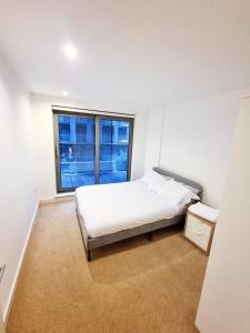 a white bedroom with a bed and a window at Your Riverside Home 3 with Private balcony in Woolwich