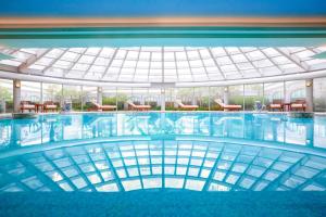 a swimming pool with tables and chairs in a building at Shanghai Marriott Hotel Hongqiao in Shanghai