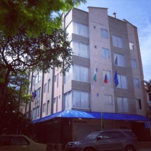 a building with three flags in front of it at ApartaHotel Montes Medellin in Medellín