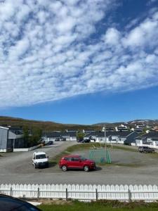 a red car parked in a parking lot with a white fence at Topview in Hammerfest