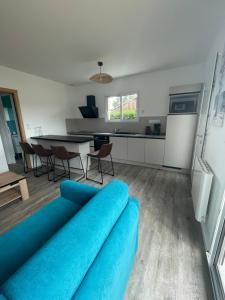 a living room with a blue couch and a kitchen at Le Porge Location neuve à 10 mn de l’océan in Le Porge