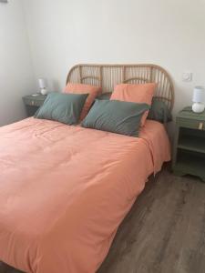 a bed with an orange comforter and two pillows at Le Porge Location neuve à 10 mn de l’océan in Le Porge