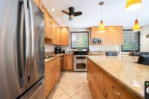 a kitchen with wooden cabinets and a stainless steel refrigerator at Hale Hui Kai in Wailea