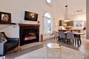 a living room with a fireplace and a dining room at Cap Magog! Près du lac Memphrémagog et Mont Orford in Magog-Orford