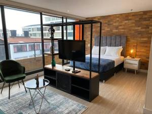 ein Schlafzimmer mit einem Bett und einem TV in einem Zimmer in der Unterkunft 512 Hermoso loft con balcón in Bogotá