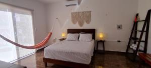 Casa Mahe, Chelem, Yucatán في تشيليم: غرفة نوم بسرير ومصباحين ونافذة