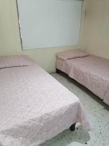 two beds in a room with pink covers on them at Casa Tajín in Monterrey
