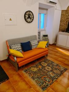 an orange couch in a living room with a clock on the wall at O beiral das andorinhas in Moura