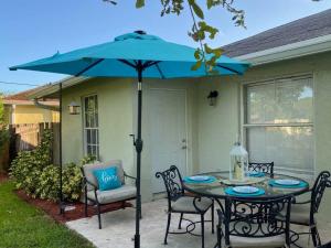 uma mesa com um guarda-chuva azul em frente a uma casa em Spacious Home Near Downtown & the Beach em Delray Beach