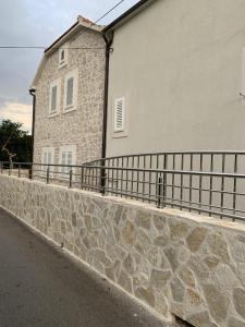 a stone wall next to a building with a fence at Beach House Murter in Murter