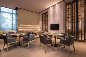 QingpuにあるCourtyard by Marriott Shanghai Hongqiaoのテーブルと椅子、薄型テレビ付きのレストランを提供しています。