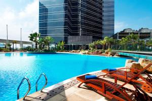 a large swimming pool with chairs and a building at Sheraton Shenzhen Futian Hotel in Shenzhen