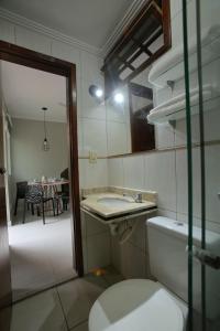 a bathroom with a toilet and a sink and a table at Estúdio com Ar Refrigerado a 300 m Praia in Cabo Frio
