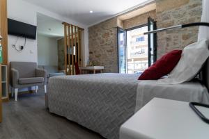 um quarto de hotel com uma cama e uma cadeira em ALOJAMENTO GIRASSOL - Guest House - Quarto com casa de banho privativa em Castelo Branco