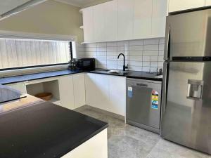 uma cozinha com um frigorífico de aço inoxidável e um lavatório em Granny Guest house Sydney Blue Mount em Kingswood