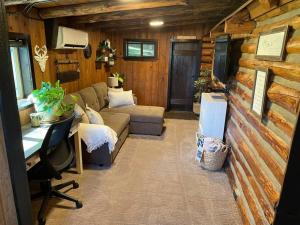 a living room in a log cabin with a couch and a desk at Little Cabin in the Woods. in Post Falls