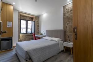 um quarto com uma cama, uma cadeira e uma janela em ALOJAMENTO GIRASSOL - Guest House - Quarto com casa de banho privativa em Castelo Branco