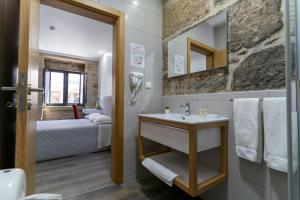 uma casa de banho com um lavatrio e uma cama num quarto em ALOJAMENTO GIRASSOL - Guest House - Quarto com casa de banho privativa em Castelo Branco