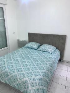 - un lit avec une couette bleue et 2 oreillers dans l'établissement Appartement 1 chambre proche Gare RER B Vert Galant - Parking et balcon privé - Proche Aéroport Roissy CDG - Parc Des Expositions - Paris - Stade de France - Astérix - Disneyland Paris, à Villepinte