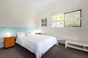 a white bedroom with a bed and a window at Valley Farm Vineyard Villas in Healesville