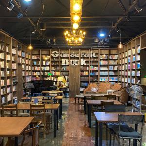 biblioteca con mesas, sillas y libros en Ganderak Guesthouse en Jeju