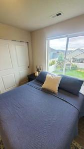 Un dormitorio con una cama azul con una ventana grande. en Family Fun! Gorgeous North Idaho Home w/Tesla Charge : Prairie Inn, en Post Falls