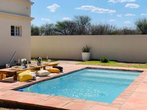 una piscina en un patio trasero con una mesa y una mesa de picnic en Mmaset Houses bed and breakfast en Gaborone