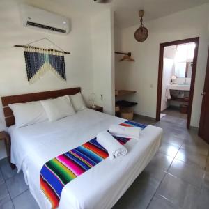 1 dormitorio con cama blanca y manta colorida en Blue Mahahual, en Mahahual