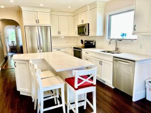 a kitchen with white cabinets and a counter with a red seat at Crescent Heights Majesty in Calgary
