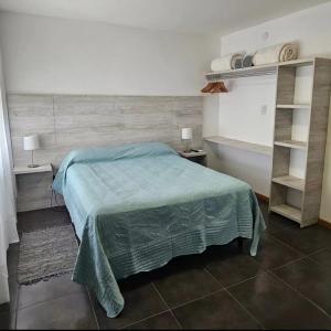 una camera con letto con coperta verde e scaffali di Hotel Miceli a Bragado