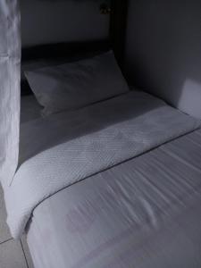 uma cama com lençóis brancos e almofadas num quarto em HABITACIÓN COMPARTIDA MIXTA EN MIRAFLORES DE FAMILIA CON PRINCIPIOS Y VALOREs em Lima