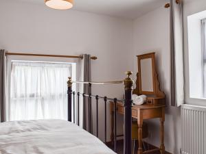 a bedroom with a bed and a mirror and a window at Voelas Cottage Annexe in Llong