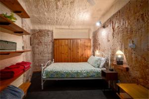 a bedroom with a bed in a stone wall at Dinky Di's Dugout in Coober Pedy