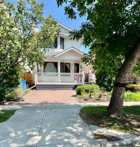 una casa bianca con un portico e un albero di Crescent Heights Majesty a Calgary
