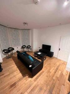- un salon avec un canapé noir et des chaises dans l'établissement 2 bed garden flat West Dulwich FREE STREET PARKING, à Londres