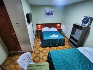 una camera d'albergo con due letti e una televisione di Hostal Continental a Nazca