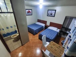 Habitación pequeña con 2 camas y mesa. en Hostal Continental, en Nazca